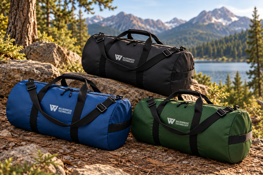 Wilderness Technology Heavy Duty Duffels in black, blue and green on a rocky trail above a mountain lake